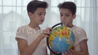 黑种人白人小学生拿着地球仪，向他的孪生兄弟解释地理的特写照片。 兄弟姐妹